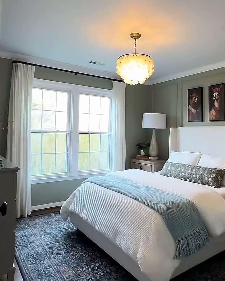 Bedroom with sage walls, a crystal pendant and a pair of windows