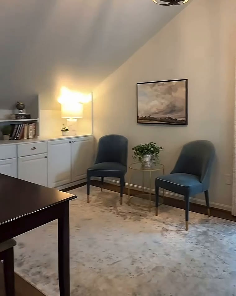 Vaulted sitting room with built-in cabinets, two blue chairs and a wall sconce