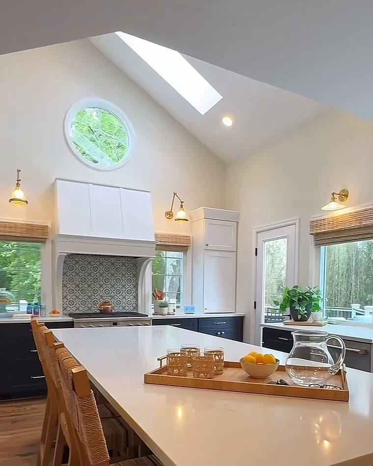 Long white kitchen island with wooden stools and navy lower cabinets