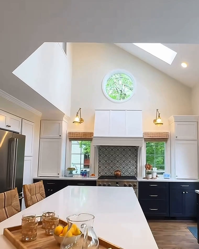 Kitchen with a vaulted ceiling, skylights and a round window above a white range hood