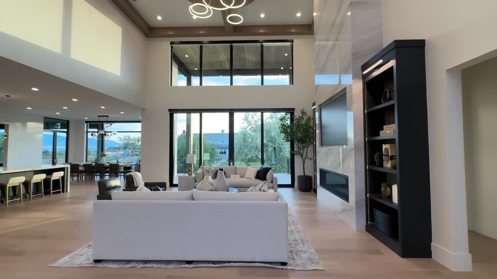 Double-height great room with a wall of windows and black built-in shelving