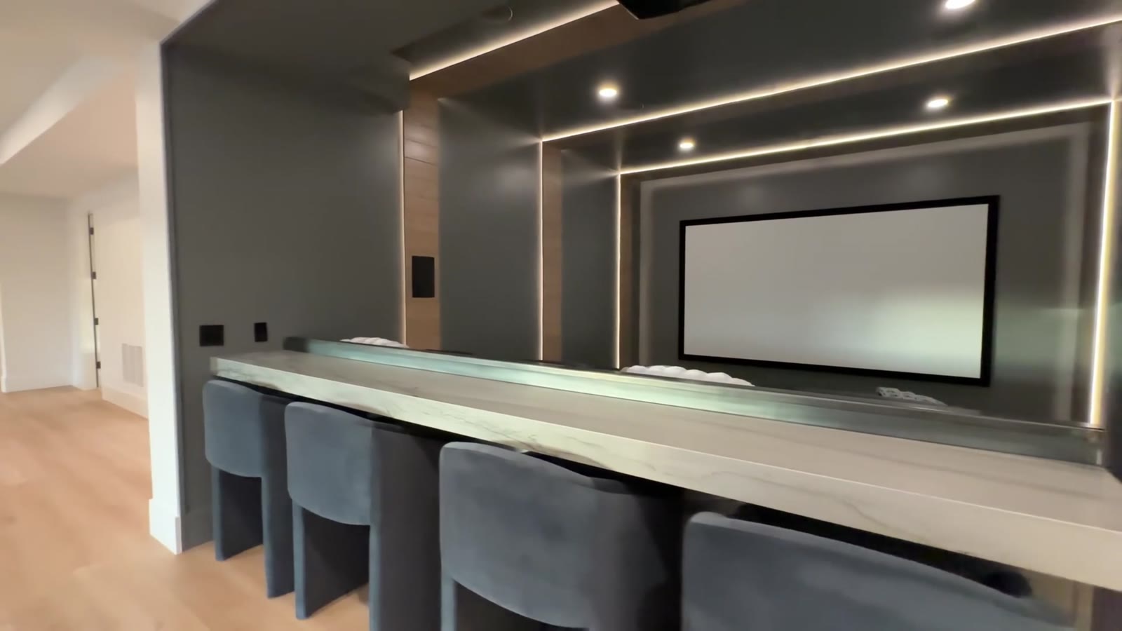 Private theater with projection screen and lit wall panels