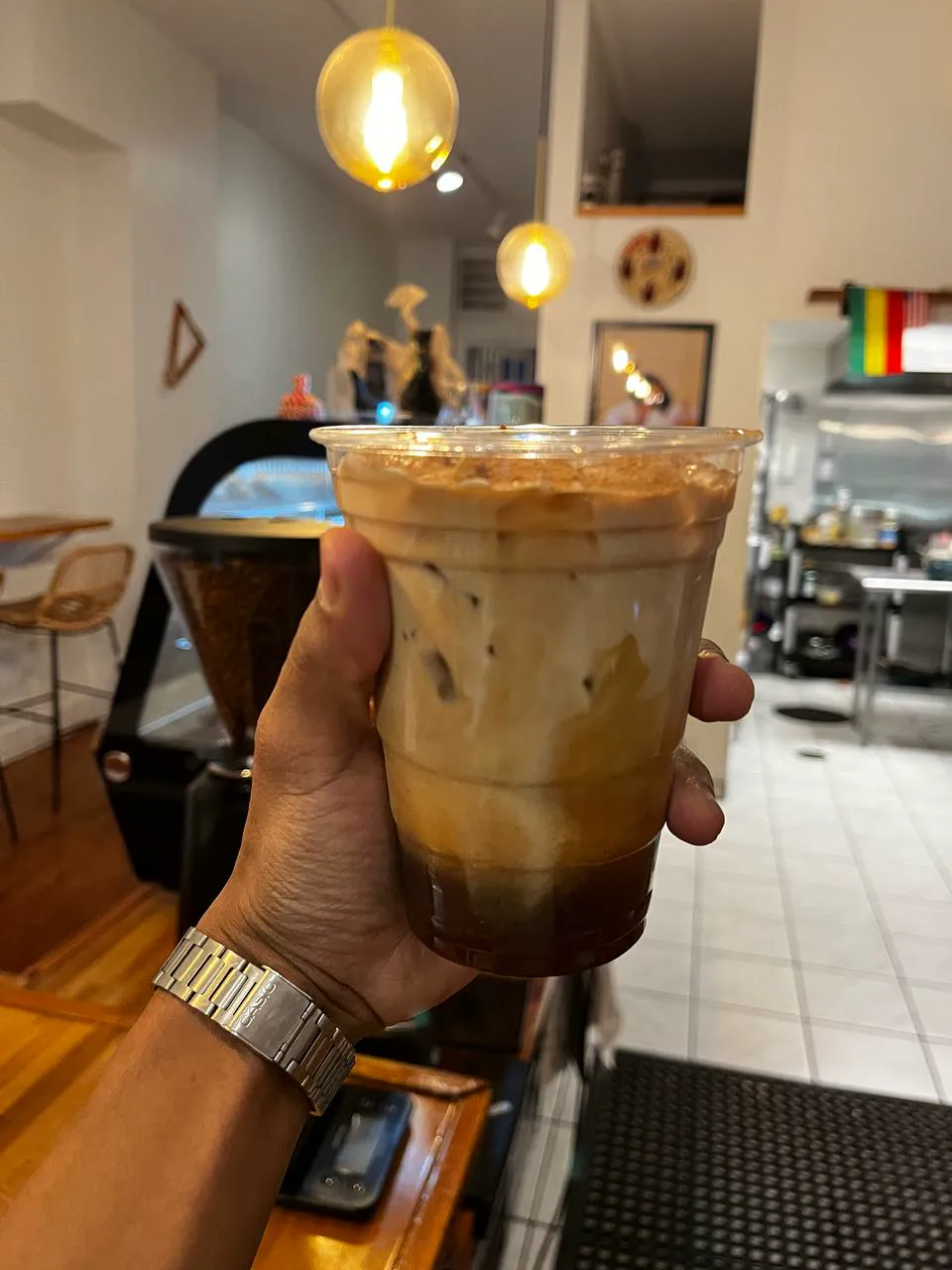 An iced latte held up in front of the bar