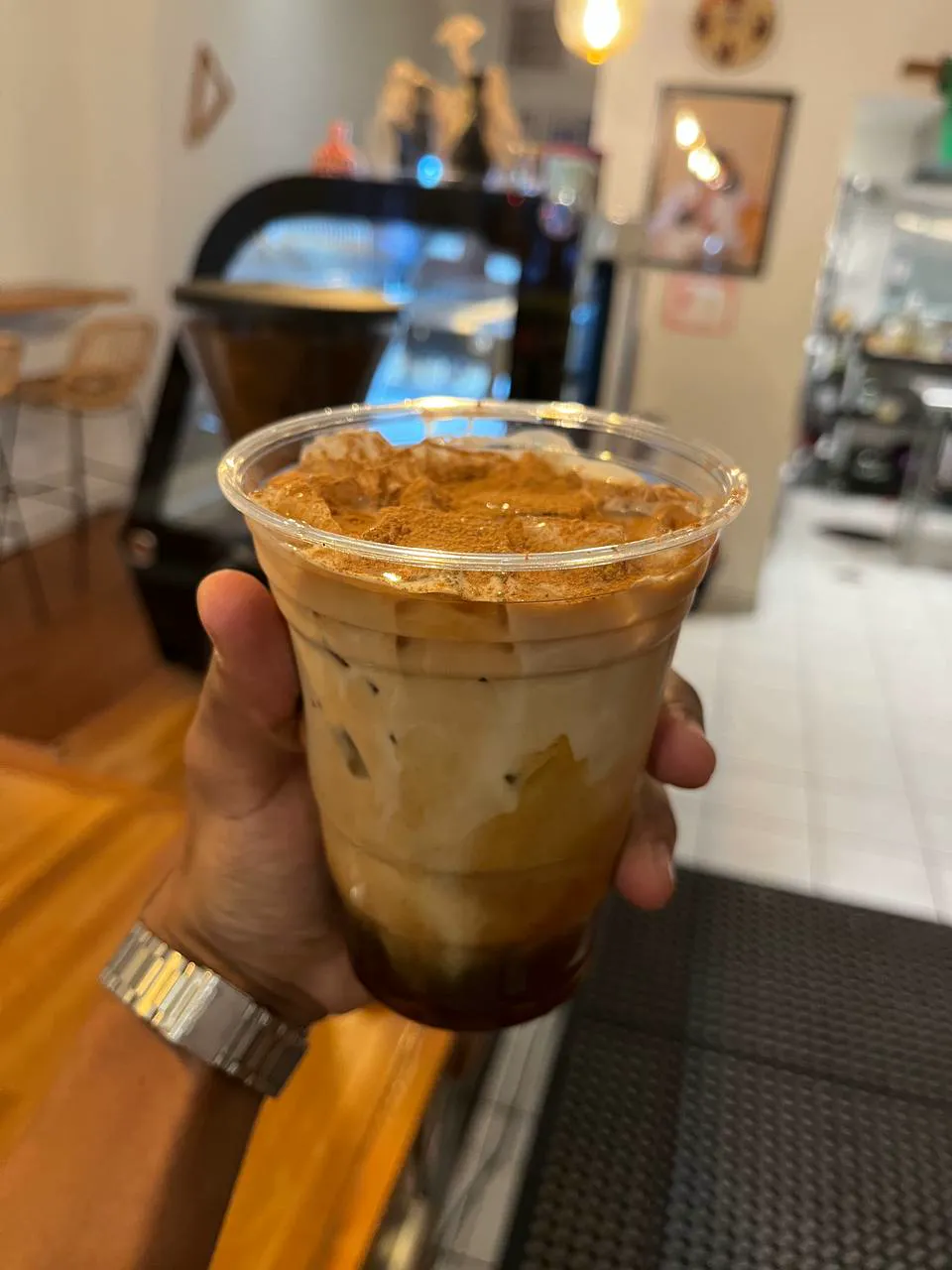 An iced latte in a clear cup with spice dusted on top