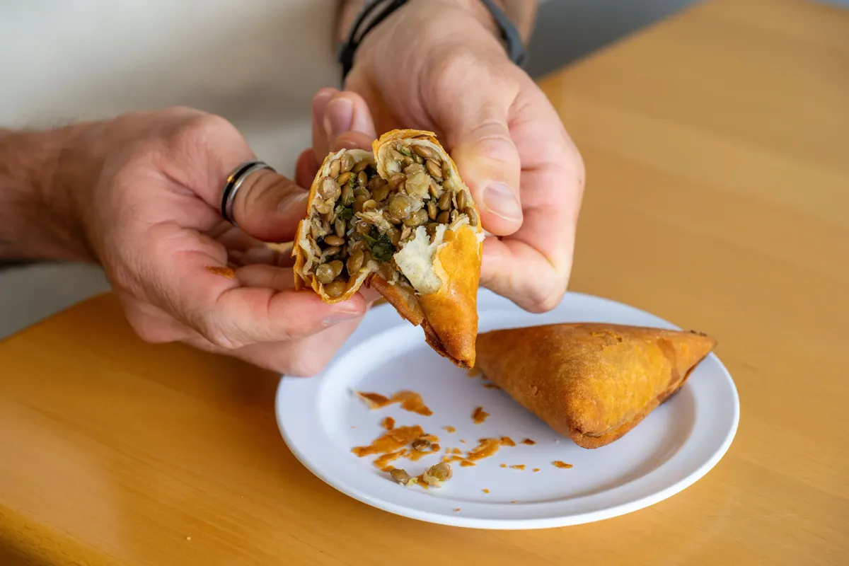 A sambusa broken open to show its lentil filling