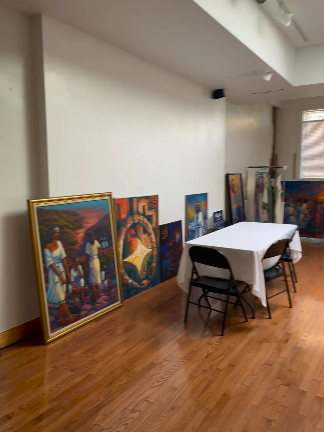 Large framed paintings of Ethiopian scenes leaning against a white wall in the event space