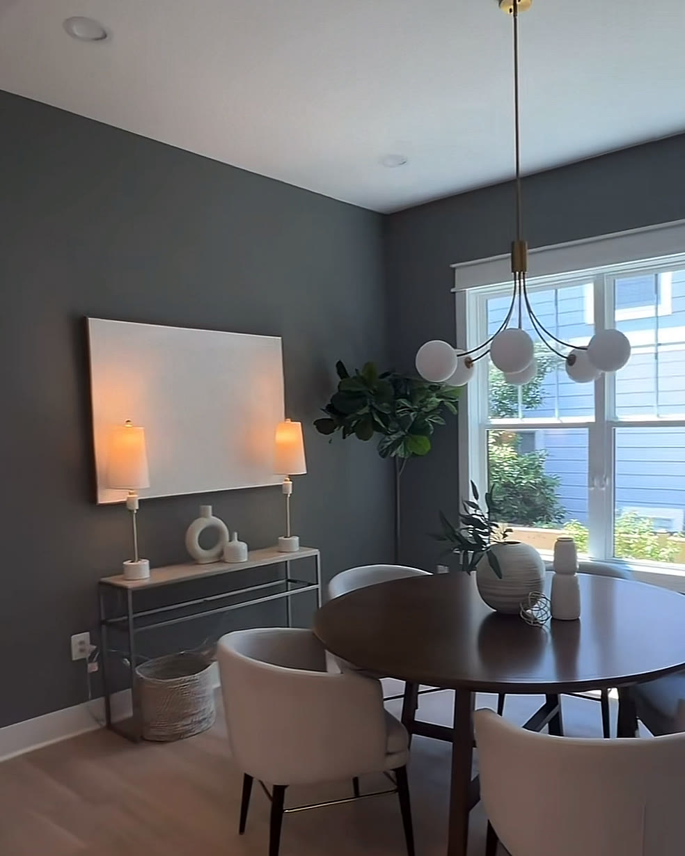 Dining room with a charcoal accent wall, round table and globe pendant light