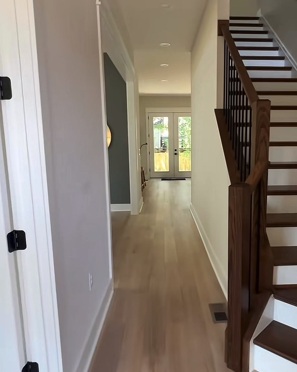 Foyer with light wide-plank floors and a dark wood staircase with black balusters
