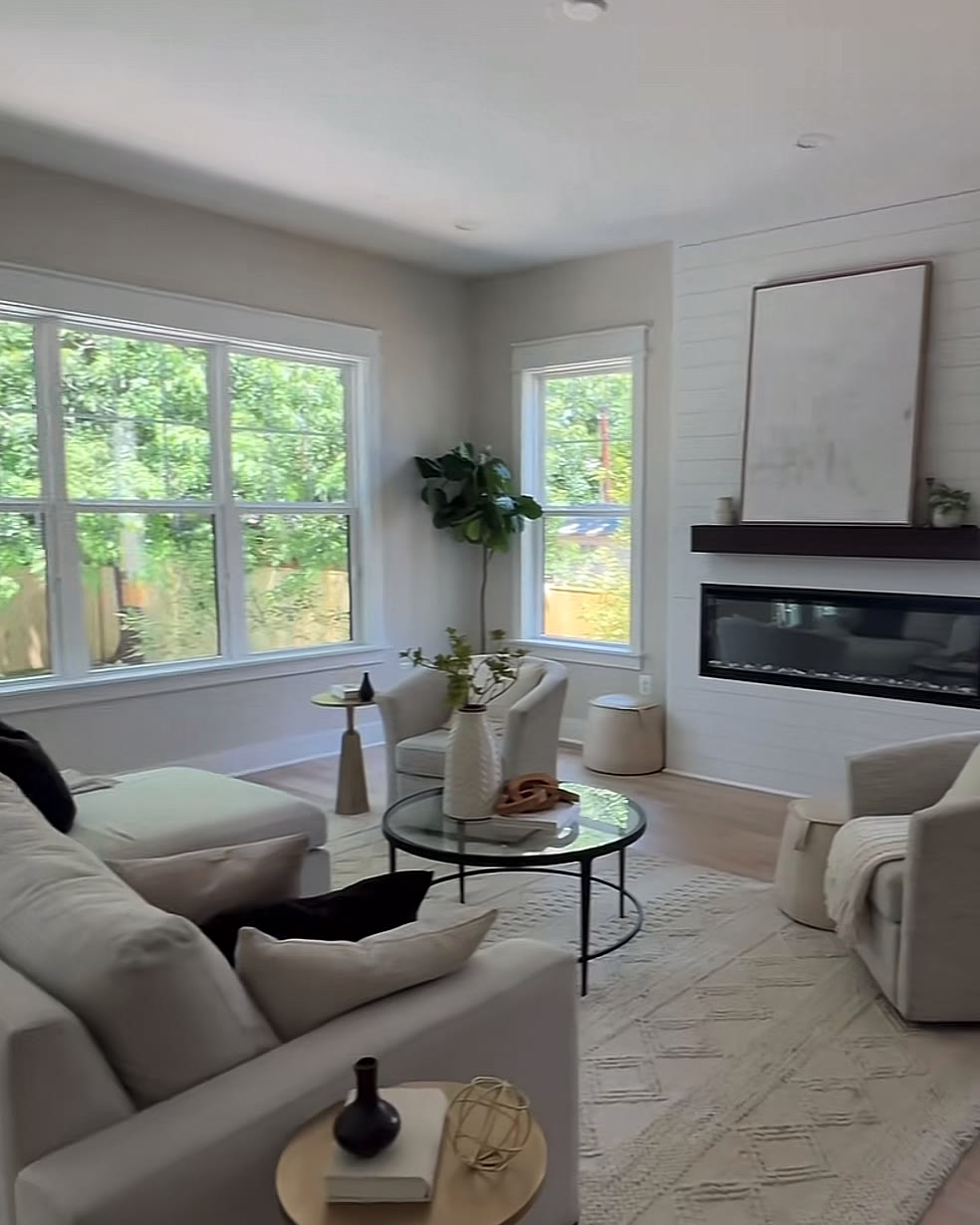 Living room with a linear fireplace, white sofas and French doors opening toward the pool