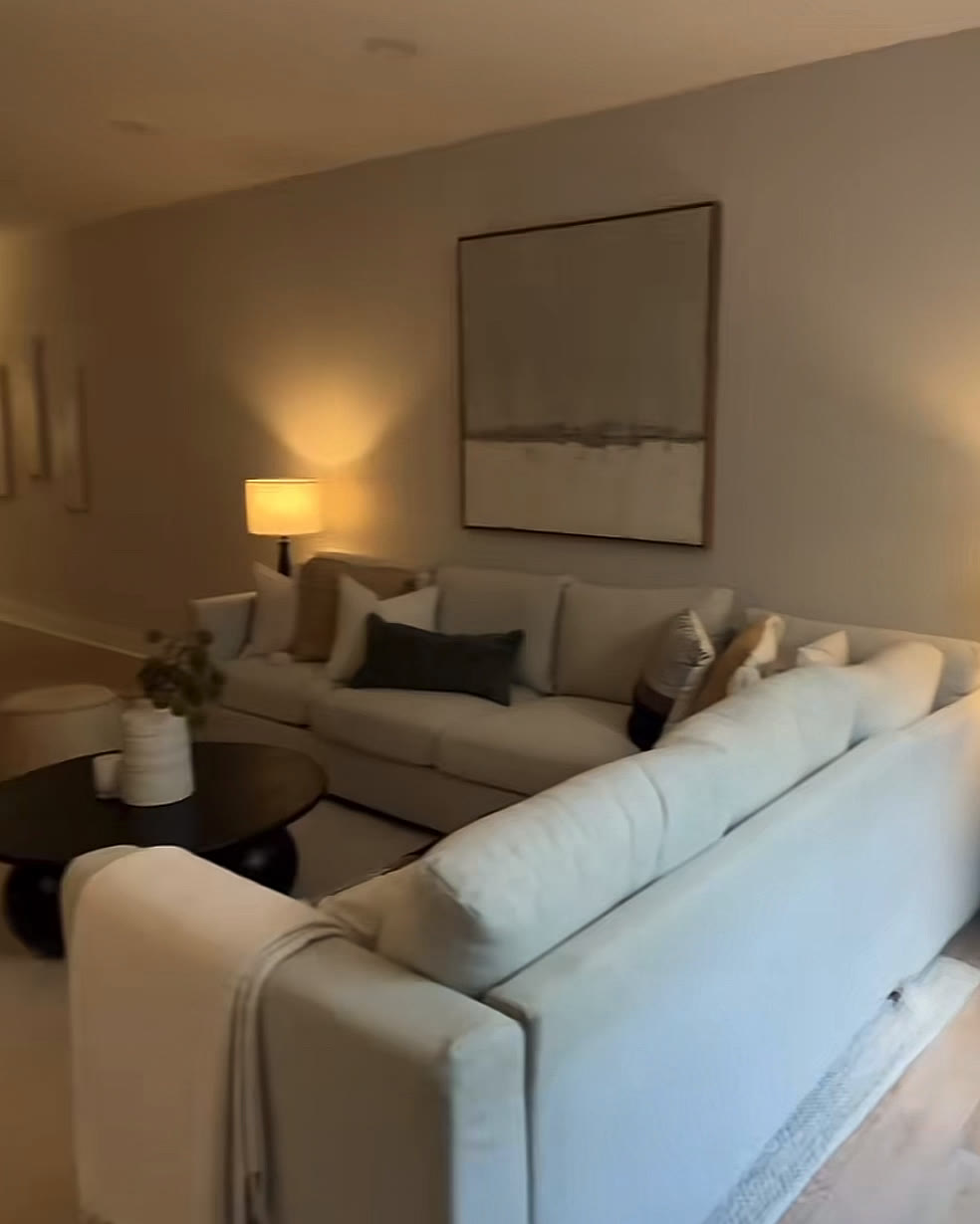Lower-level lounge with a white sofa, framed art and warm table lamps