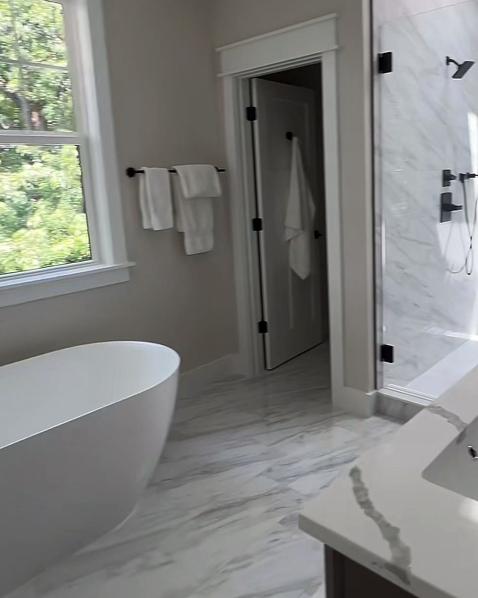 Primary bathroom with a freestanding soaking tub and marble-look tile
