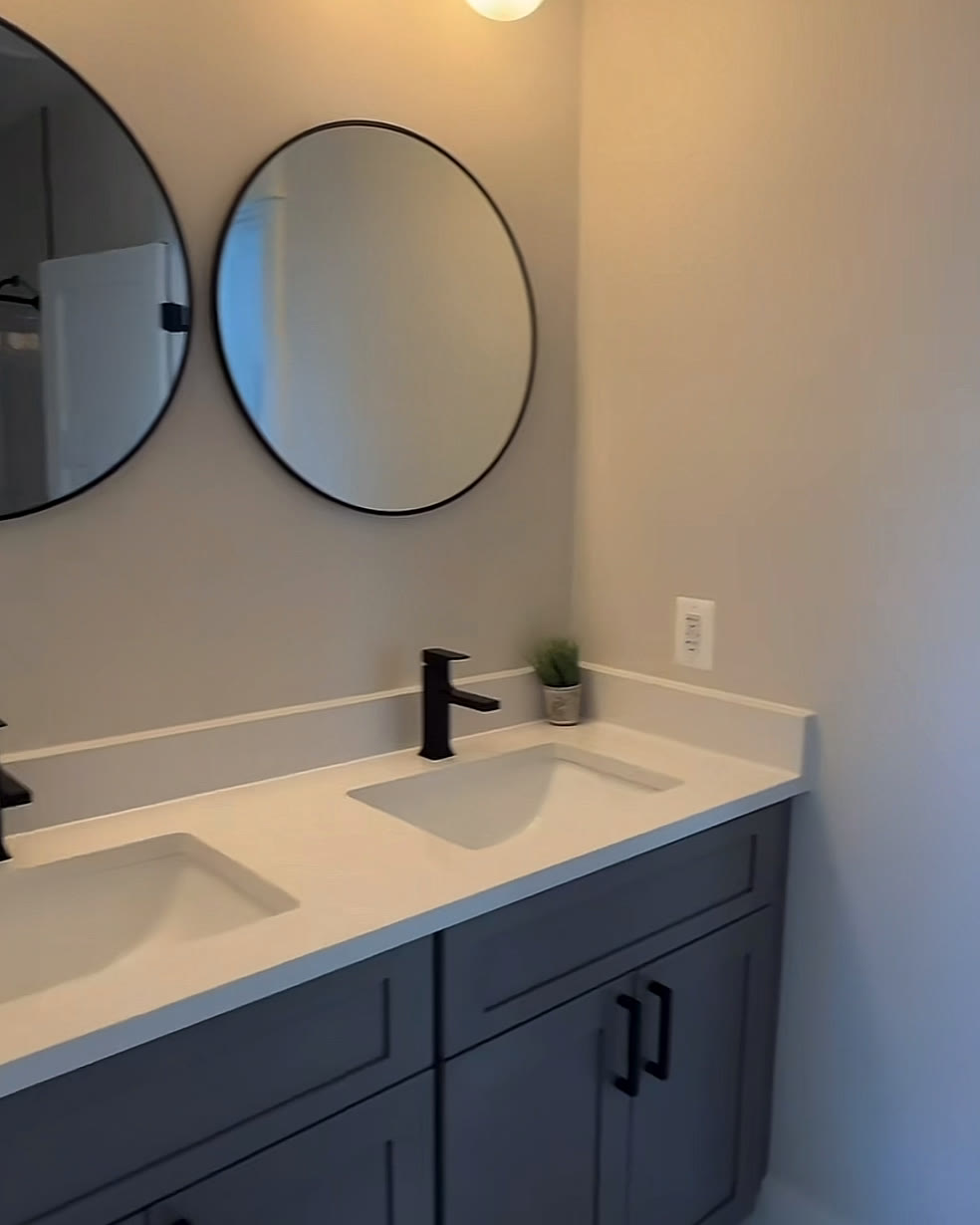 Bathroom with a navy double vanity and two round black mirrors