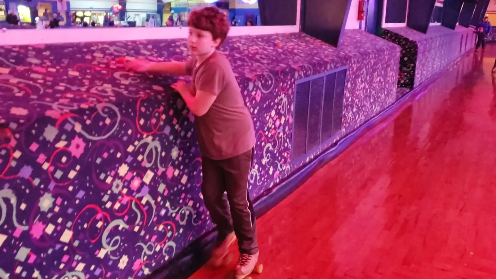 A young skater resting on the carpeted rail wall with its purple confetti pattern.