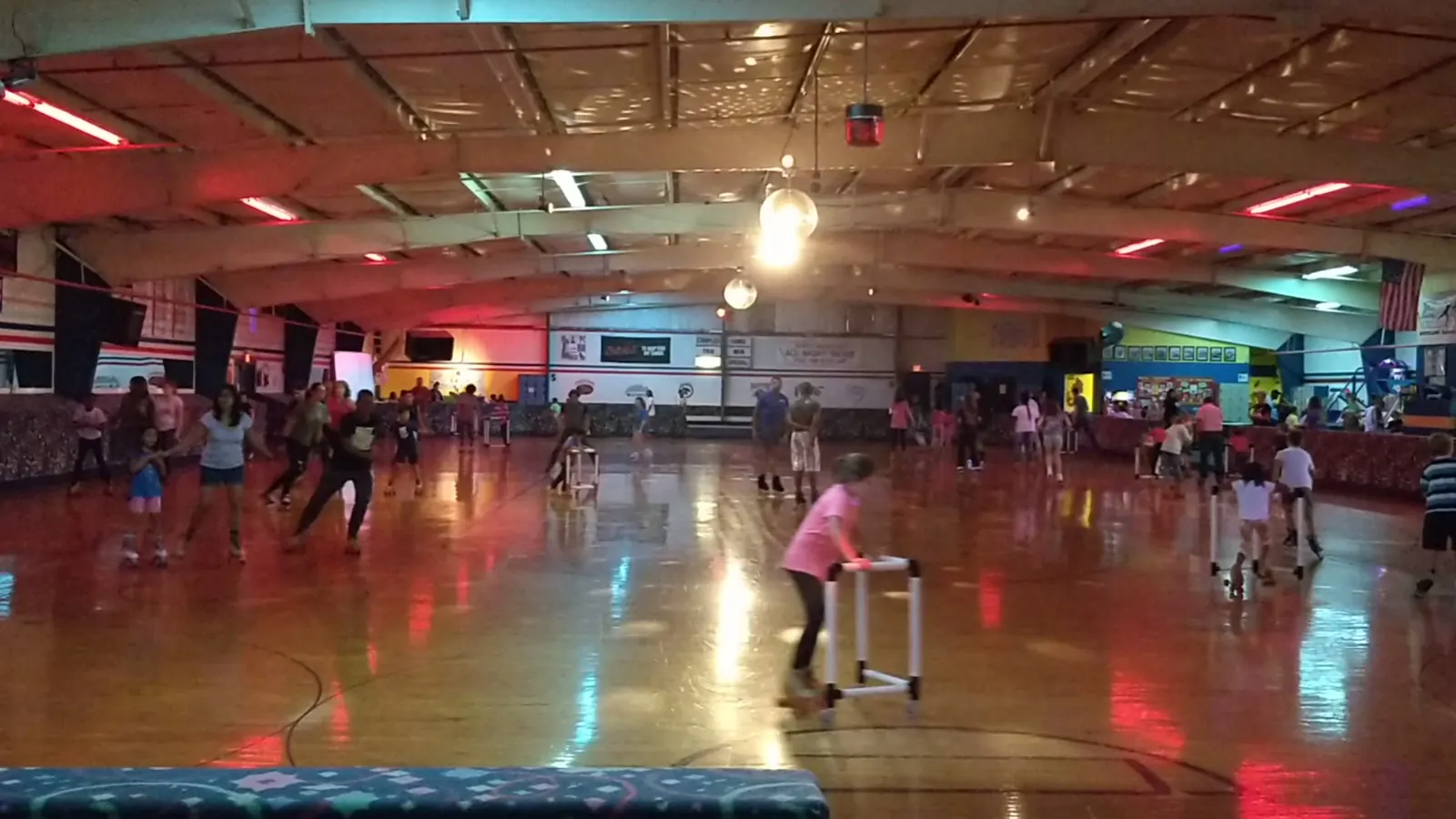 A busy session with dozens of skaters circling the rink under colored lights.
