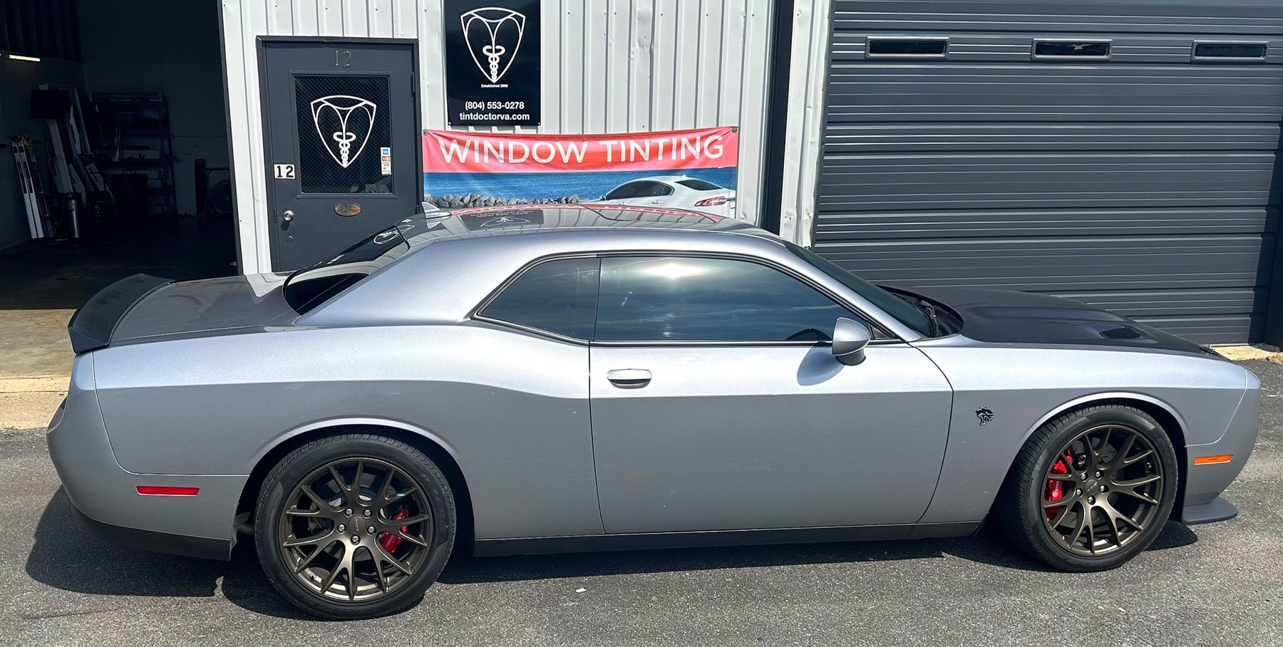 Silver Dodge Challenger with tint in front of the shop